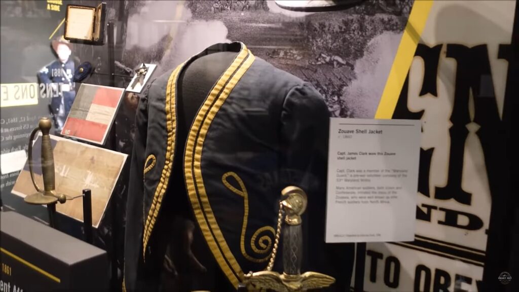 mannequin dressed in military uniform behind glass and sheet with information on it